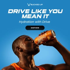 Athlete drinking a Bucked Up Drive Hydration energy drink against a blue sky background